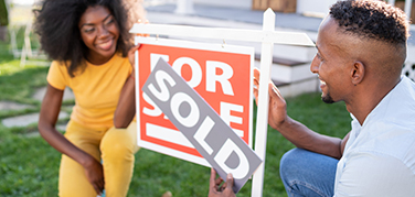 Woman and man next to a sold sign